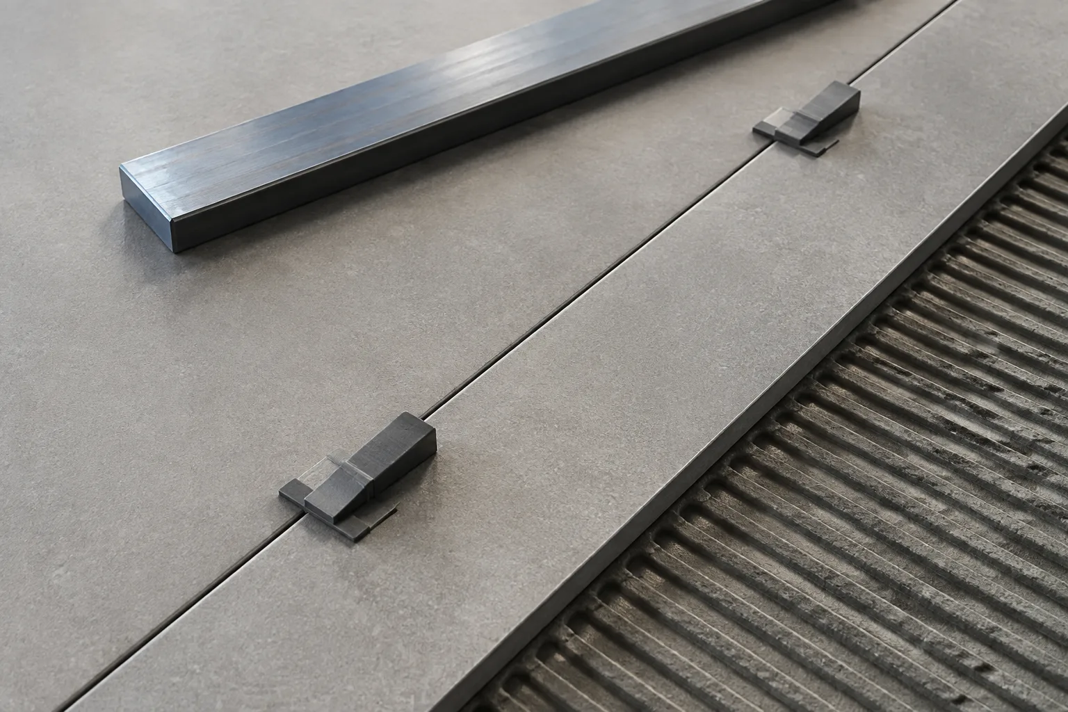 Zwei matte Keramikplatten werden mit neutralen Nivellierhilfen an einer gleichmässigen Fuge ausgerichtet.